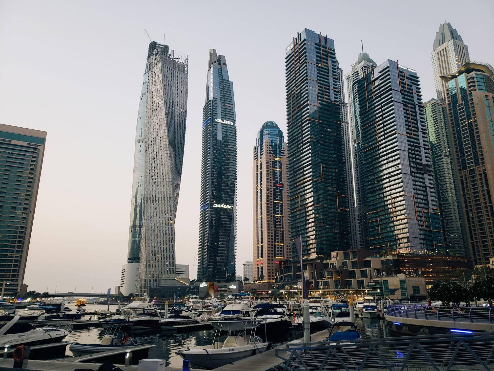 Dubai Marina at dusk with Cayan Tower and the Marina towers above the yacht berths
