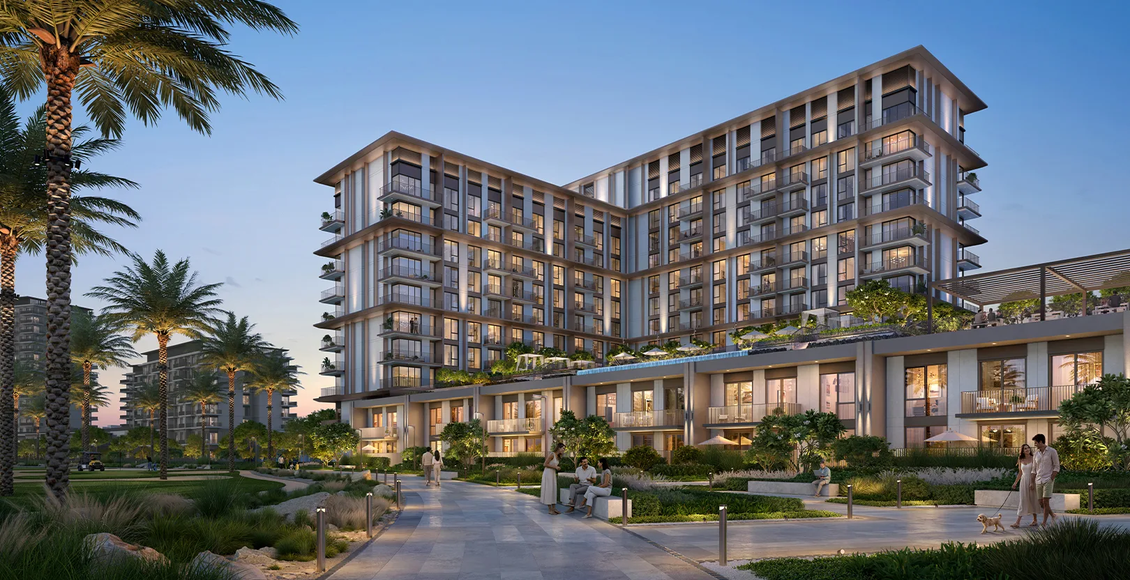 L-shaped tower with podium townhouses at dusk
